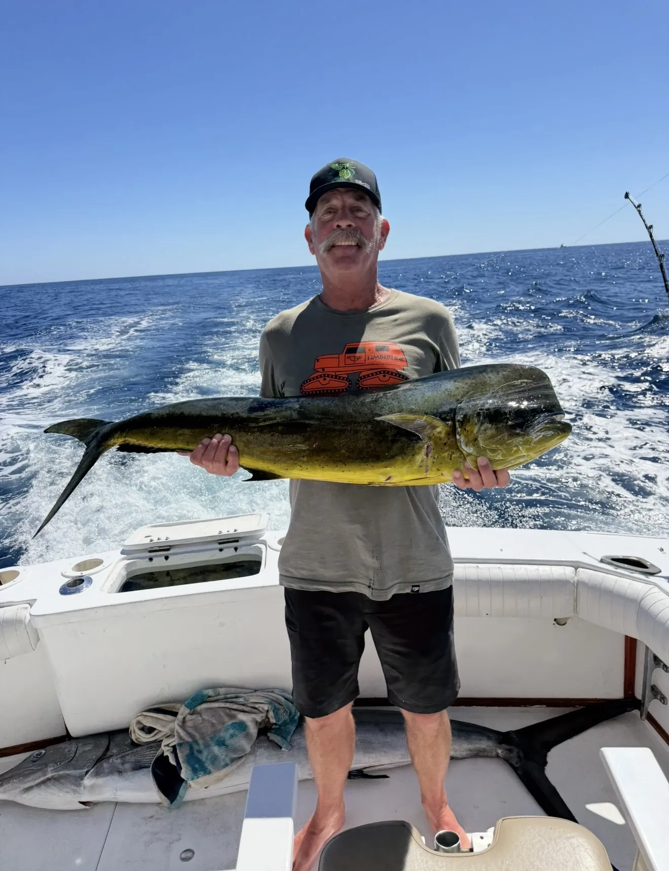 Guest holding a dorado on the stern with another catch on deck