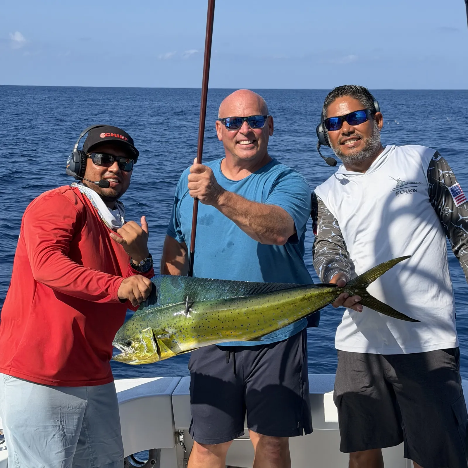 Three guests holding a bull dorado on the deck of the Hatteras off Cabo San Lucas