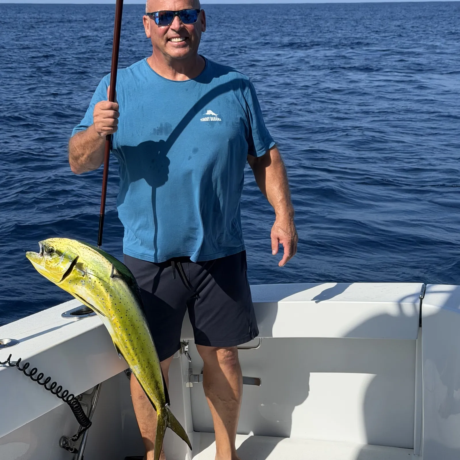 Guest holding a dorado on the stern in open blue water