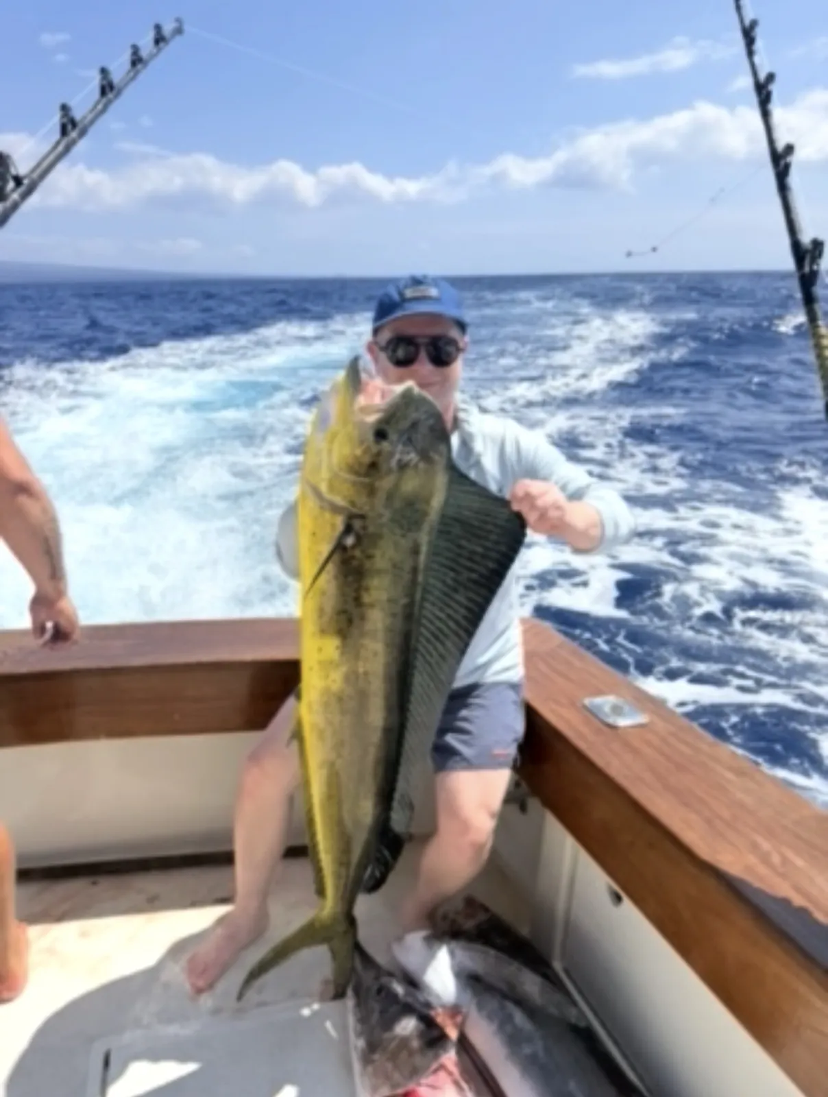 Guest holding up a dorado over the wake of the Hatteras