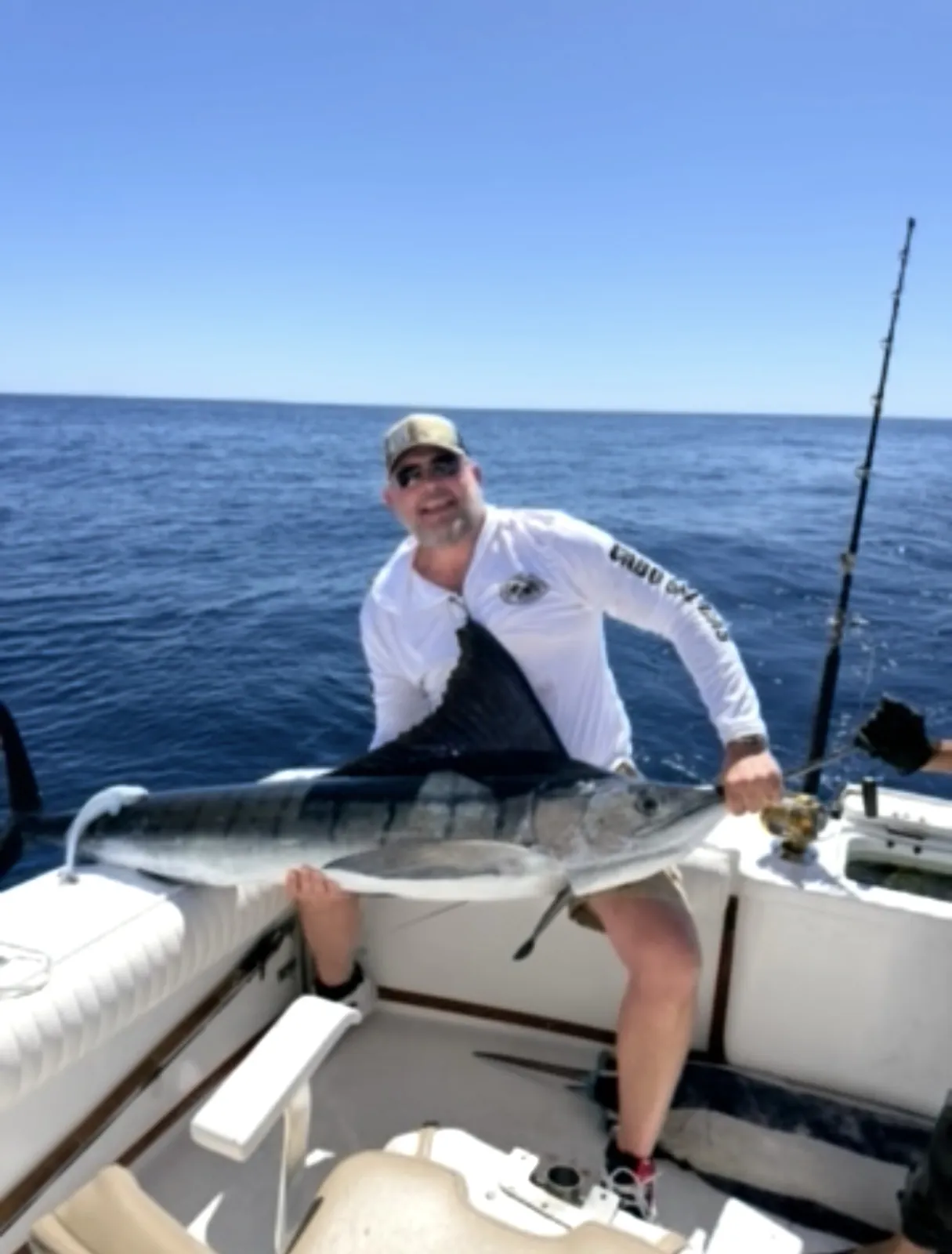 Guest kneeling beside a striped marlin on the deck before release
